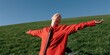 © Andrii Zastrozhnov - Close-up man in red shirt stretching open arms on green hill with laptop for outdoor remote work background and freedom lifestyle banner design