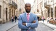 © PhanDesigns - A confident black businessman wearing a blue suit and pink tie in an urban setting.