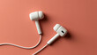 © Rajims Creations - Exclusive photo of White wired earbuds placed on a soft coral pink background. Ideal for music, podcasting, and modern technology marketing campaigns.