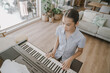 © SewcreamStudio - piano, keyboard, girl, music, playing, practice, student learning to play a digital instrument in a bright modern living room, focused young musician developing her talent at home.