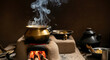 © Feri - Traditional brass pot cooking on a clay stove with rising steam and burning firewood