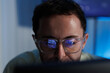 © SAT65 - Focused Software Developer Writing Programming Code with Code Reflected on Glasses While Working at Computer. Software engineer concentrating on programming while looking at monitor with computer code