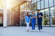 © Dragana Gordic - Smiling Medical Team Walking and Talking Outside Modern Hospital Building During Daytime Shift