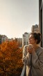 © Micevic family - Woman enjoying a warm cup of coffee by a window on an autumn morning