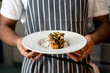 © JPH Photo - Chef Showcasing a Beautifully Plated Gourmet Dish at a Bustling Restaurant Kitchen