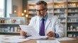 © Thongphun - Reviewing insurance prior authorization forms and tiered formulary documents, a pharmacist in professional business attire works at a wide desk.