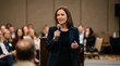 © Elenba - Woman giving a public speech at a conference. Professional speaker holding a microphone in front of an audience