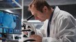 © DC Studio - Male scientist investigates tray samples under optical microscope