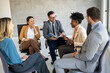 © NDABCREATIVITY - Multicultural professional businesspeople working together on research plan in boardroom.