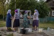 © Dmitry - Women collecting water with buckets at a traditional village well. Rural community life, shared responsibility, access to clean water, and cultural documentary scene.