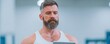 © Phanupong - Middle aged man with beard using digital tablet in gym for fitness technology tracking and workout planning to monitor exercise progress and health data