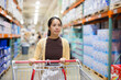 © leungchopan - Woman pushing shopping cart inside large wholesale store