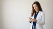 © MariaMedeiros - Female doctor in white lab coat typing text message on smartphone against white background with mobile phone using phone hospital staff
