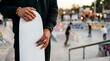 © Yuliia - Pregnant woman with dark skin tone wearing black clothing holding her