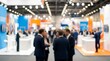 © LA Stock Vision - Business people networking at an exhibition booth during a busy trade show.