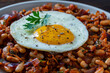 © OlegD - Fried egg on top of baked beans with vegetables, closeup. Delicious sunny-side-up fried egg seasoned with black pepper and parsley served over warm rich stew of white beans with tomatoes and onions