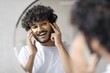 © Prostock-studio - Smiling Young South Asian Man Enjoying Skincare Routine By Applying Eye Patch Treatment In Front Of Mirror At Home. Focused On Personal Care And Wellbeing In Cozy Indoor Setting.