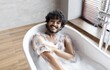 © Prostock-studio - Smiling Young Man With Curly Hair Enjoying A Relaxing Bath In Bathtub Filled With Bubbles At Home, A Moment Of Calmness And Self-care In A Modern Bathroom, Wellness Concept.