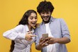 © Prostock-studio - Smiling Young Multiracial Couple Excitedly Pointing At Smartphone While Exploring Content Together In Bright Yellow Studio Environment. Engaging Lifestyle Concept With Technology.