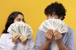 © Prostock-studio - Happy Young South Asian Couple Holding Cash Money Bills, Smiling And Looking At Each Other In Studio Setting. Excitement And Joy Of Financial Success And Prosperity, Business Concept.