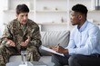 © Prostock-studio - Worried Caucasian Male Soldier In Camouflage Uniform Engaging In Therapy With African American Male Therapist At Office. Discussing Mental Health Issues, Seeking Support In Professional Environment.