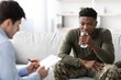 © Prostock-studio - Worried Black Male Patient In His 30s Processing Information While Drinking Water During Consultation With Therapist At Office, Seeking Help And Support In Healthcare Concept.