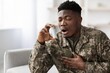 © Prostock-studio - Worried Black Male Soldier Experiencing Breathing Difficulty While Using Inhaler At Home Environment, Representing Challenges Faced By Military Personnel With Health Issues, Healthcare Concept.