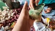© Jhaya - First Person POV Close Up Hand Giving Cash Money to Traditional Market Merchant Buying Shallots Allium cepa and Garlic