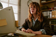 © AnnaStills - Young adult Caucasian woman working on retro computer in vintage office, typing on keyboard. Image suitable for nostalgic corporate campaigns and technology evolution concepts