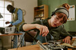 © AnnaStills - Young adult Caucasian woman repairing vintage electronics in retro office while African American colleague works in background, ideal for engineering and technical education campaigns