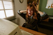 © AnnaStills - Shocked Caucasian young adult woman pulling hair while looking at old computer screen in retro office, representing work stress. Ideal for corporate burnout campaigns