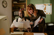 © AnnaStills - Middle aged African American man and young adult Caucasian woman reviewing documents in retro office, collaborating on vintage corporate project, medium shot