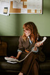 © AnnaStills - Vertical shot of young adult Caucasian woman working in retro office, dialing landline telephone. Image represents vintage corporate communication and nostalgic business marketing