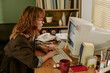 © AnnaStills - Young Caucasian woman working on retro computer in vintage office, typing on keyboard. Image represents corporate history and is suitable for technology evolution campaigns