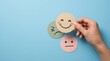 © MSTSOMAIA - Hand holding a happy smiley face paper card with other mood icons