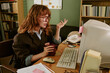 © AnnaStills - Young adult Caucasian woman working at desk in retro office, looking at vintage computer screen with confused expression. Ideal for nostalgic business and technology marketing