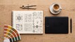 © gleni - Top-down view of a creative designer workspace with a sketchbook, graphics tablet, color palette, and compass on a wooden desk