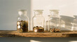© narak0rn - Consumer spending habits reflect in jars labeled spend save invest with coins inside on wooden shelf in warm light