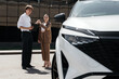© wedmoments.stock - Buyer receiving a new car key from a dealership representative beside the vehicle. Concept completed purchase, vehicle handover and automotive services.
