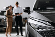 © wedmoments.stock - Modern car in close-up in a showroom while a salesperson consults buyers beside the vehicle.