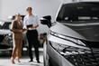 © wedmoments.stock - Contemporary car displayed in a dealership during a customer consultation. Concept vehicle purchase and automotive services.