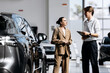 © wedmoments.stock - Car dealer advising a woman about a new vehicle before completing the purchase.