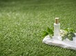 © kerkpun - A sophisticated and minimalist commercial product photography background featuring a vast, beautifully textured green lawn. The composition places a high-end cosmetic bottle on a rugged white marble s