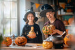 © Konstantin Yuganov - Happy Mother and Daughter Carving Pumpkins in Witch Costumes for Halloween