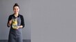 © Creative Stocker - A smiling woman wearing a dark shirt and a grey apron holding a glass pitcher filled with ad social media download thambnail poster web template event festival 2026 2027 2028