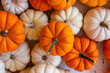 © lesley - Pile of orange and white miniature pumpkins at a farmers stand.