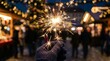 © xuxu - Close-up of a hand in a black glove holding a sparkler at a night-time Christmas market. A winter holiday celebration and a joyful tradition. An open-air market with lights and a festive atmosphere.