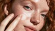 © OngCaLucK - Close-Up of a Young Woman with Freckles Applying Moisturizer to Her Face in a Natural Light Setting for Skincare Concept
