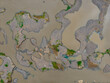 © Amazing Aerial - Aerial view of a winding river with intricate gravel bars and small patches of green vegetation emerging from the murky water in Indonesia.