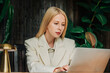 © Westend61 - Businesswoman in a white suit works on a laptop in a modern office
